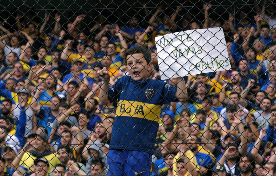  A devastated Boca fan climbs a fence holding a sign begging Carlos Tevez not to leave