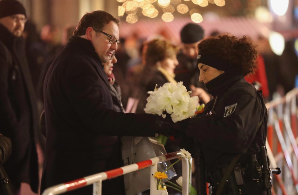  A man passes flowers to a police officer to place at the vigil