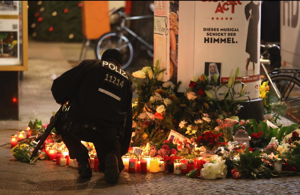  A heavily-armed policeman laid flowers last night in memory of the victims of the Berlin attack