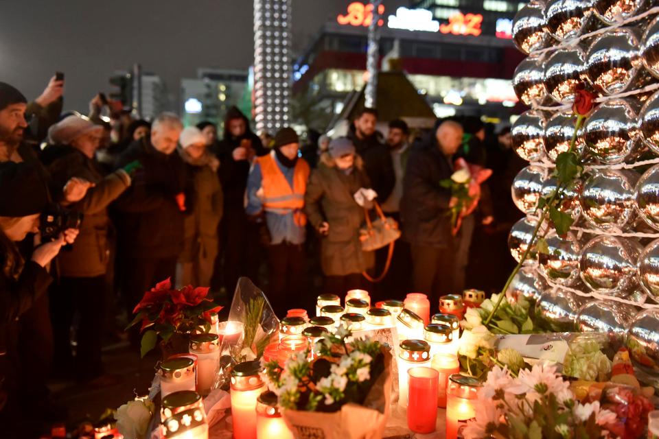  Mourners gather at the scene of the devastation, now littered with candles and flowers