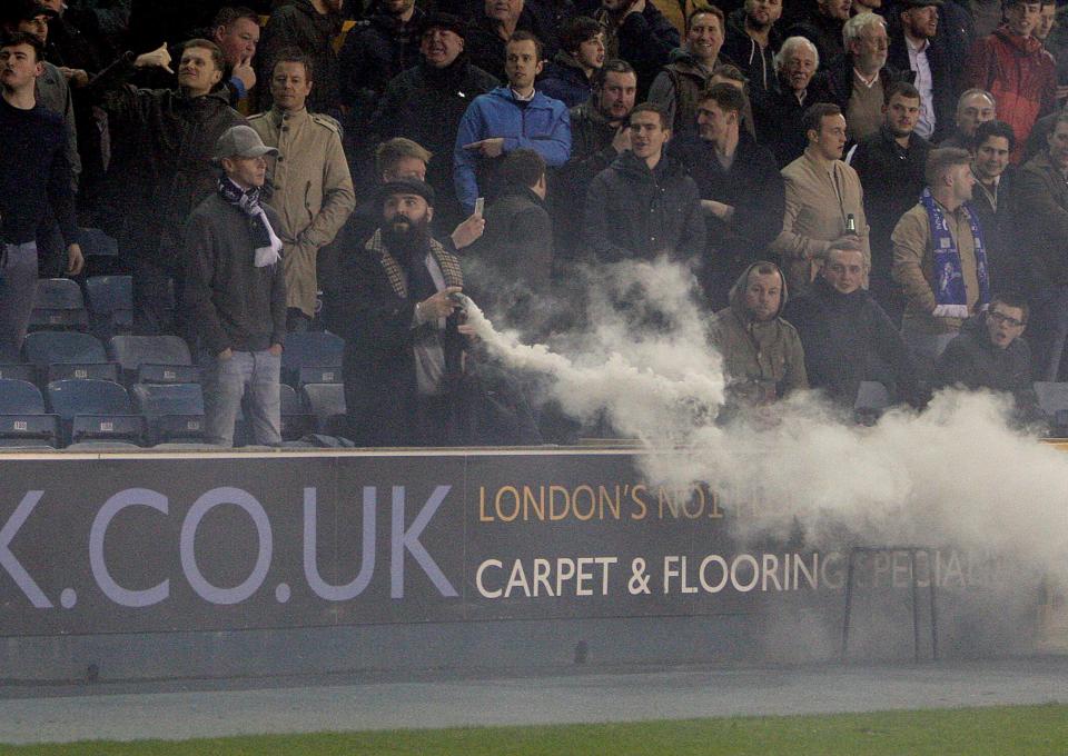  A Millwall fan takes a puff of the smokebomb