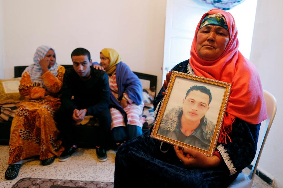  Mum Nour,65, poses with a portrait of her son in the family home in Tunisia