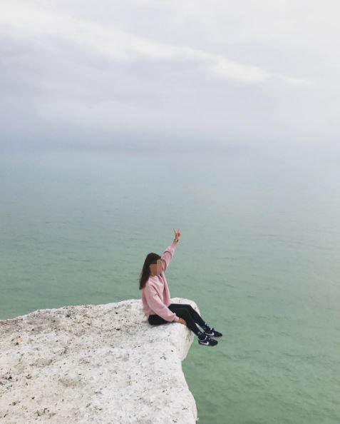  Their friend also poses on the edge of the cliff at Seven Sisters Country Park near Brighton, East Sussex