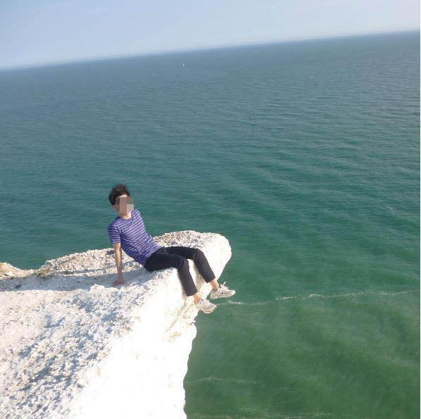  A man, who is with the group, also poses on the edge of the cliff in a move slammed by the Coastguard