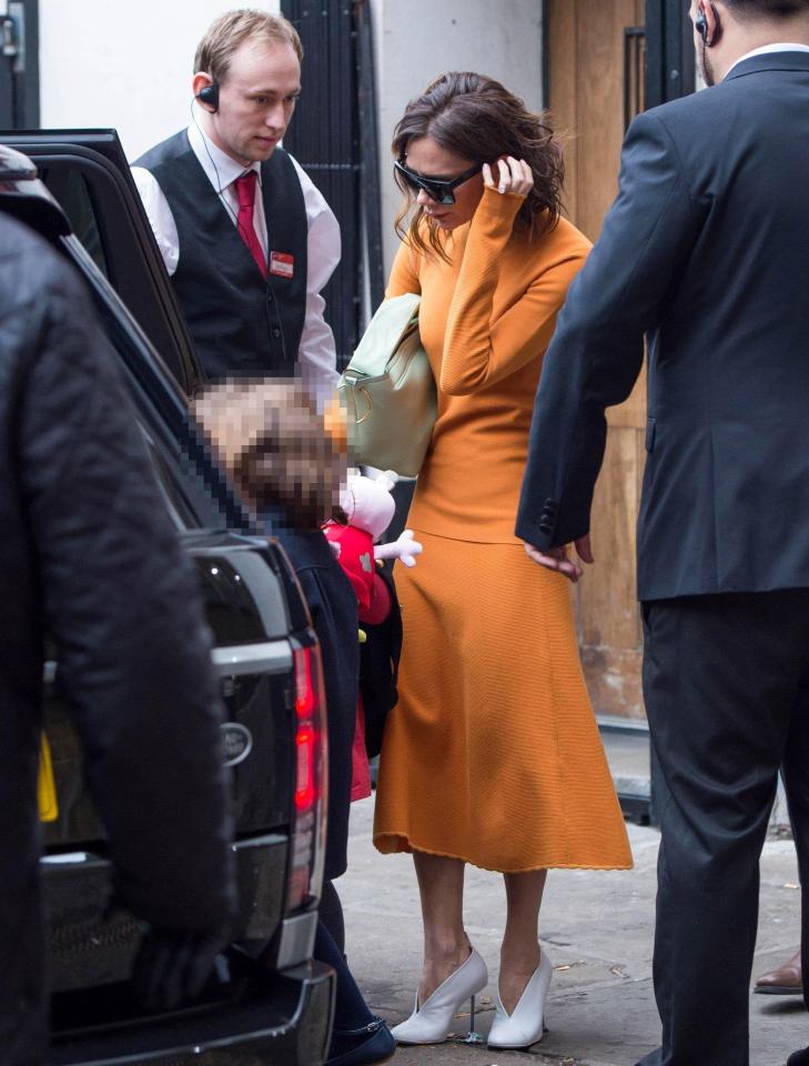  VB looked stylist dressed in an orange jumper and midi skirt, accessorising with white heel boots, a light green handbag and oversized sunglasses