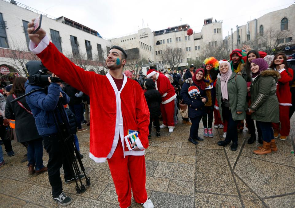  A Palestinian dressed as Santa Claus takes a selfie on Christmas Eve in the square