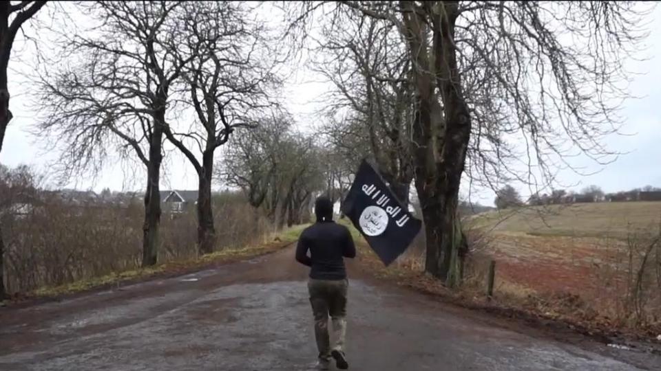  The man - carrying the Isis flag and a fake gun -walks straight across the border