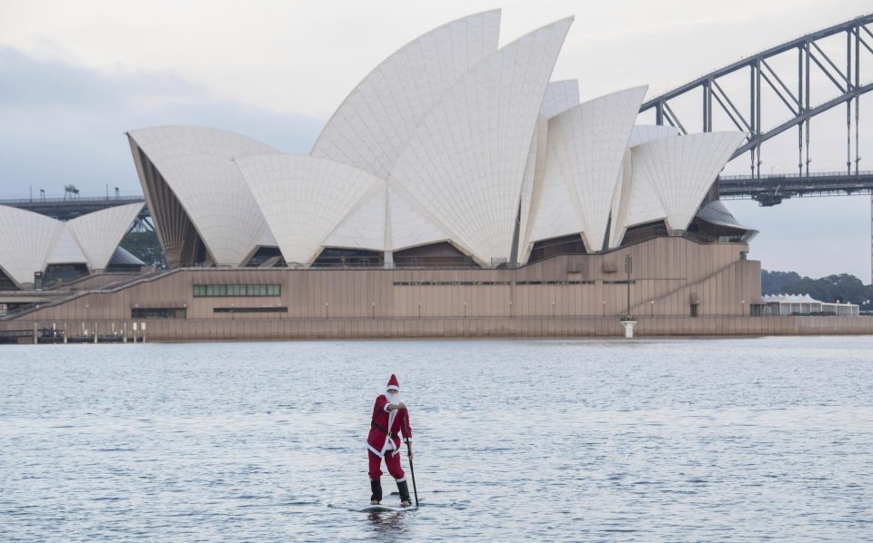  Looks like Father Christmas ditched his sleigh for a paddle board near Sydney's opera house