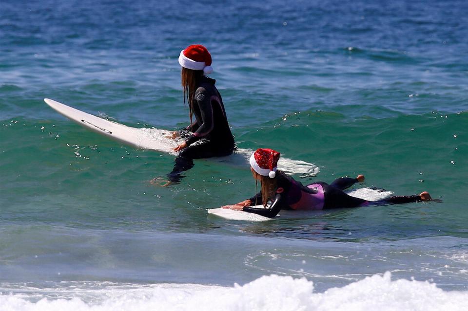  German tourists Mimi Weibeling and Pauline Lapetite wait for waves in their Christmas hats