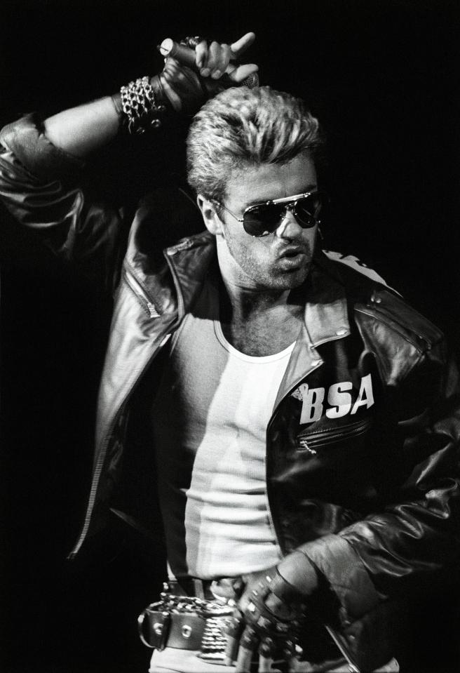  George Michael performs on stage, wearing a leather jacket and sunglasses, on the Faith Tour