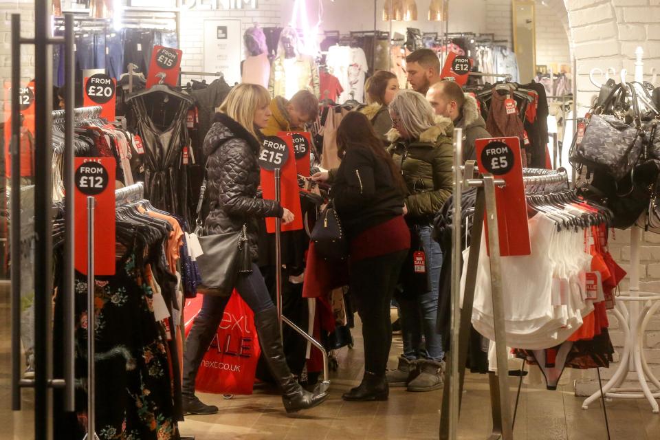  Shoppers at Briggate, Leeds rifle through items on discounted clothing racks