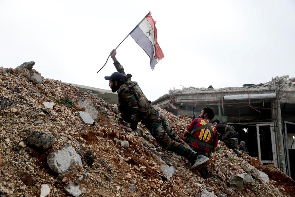  A Syrian army soldier places a Syrian national flag during a battle with rebel fighters at the Ramouseh front line, east of Aleppo