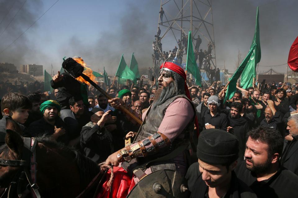  A Shiite re-enacts the events of Ashoura while Iranian and Iraqi Shiite Muslims mourn in a procession in southern Tehran