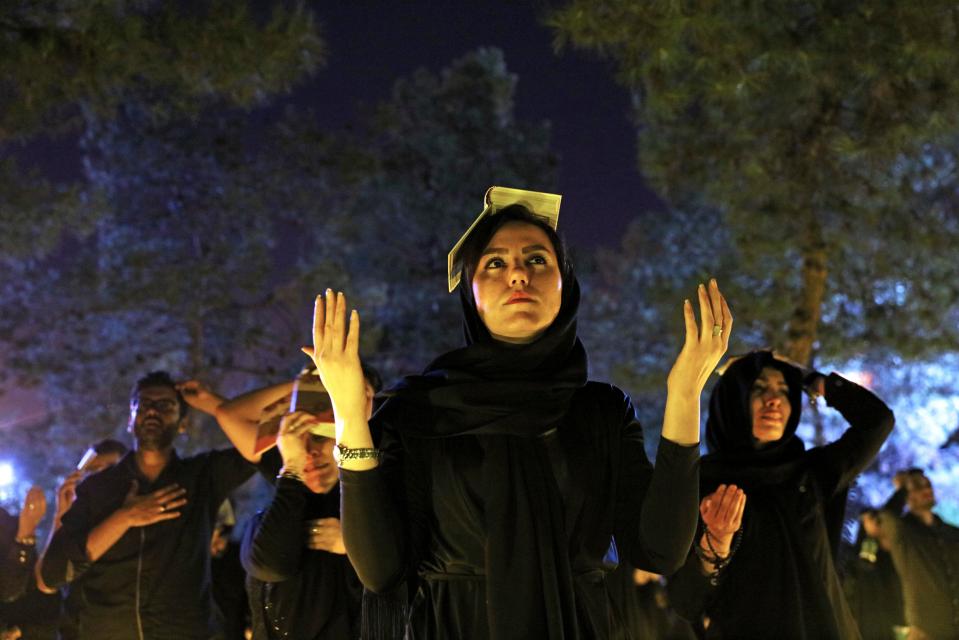  Iranian Shiite Muslims pray as they place the Quran on their heads at the graves of soldiers who were killed during 1980-88 Iran-Iraq War, at the Behesht-e-Zahra cemetery