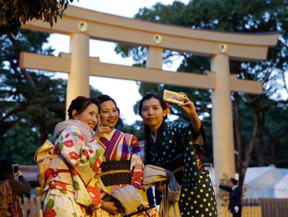  Kimono-clad women take a selfie in front of a wooden torii gate at Meiji Shrine as the shinto ritual preparing for the New Year is held at the shrine in Tokyo