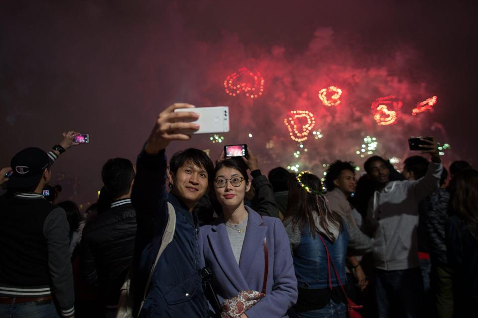  Revellers take selfies and watch a fireworks display over Victoria Harbour during New Year's Eve celebrations in Hong Kong