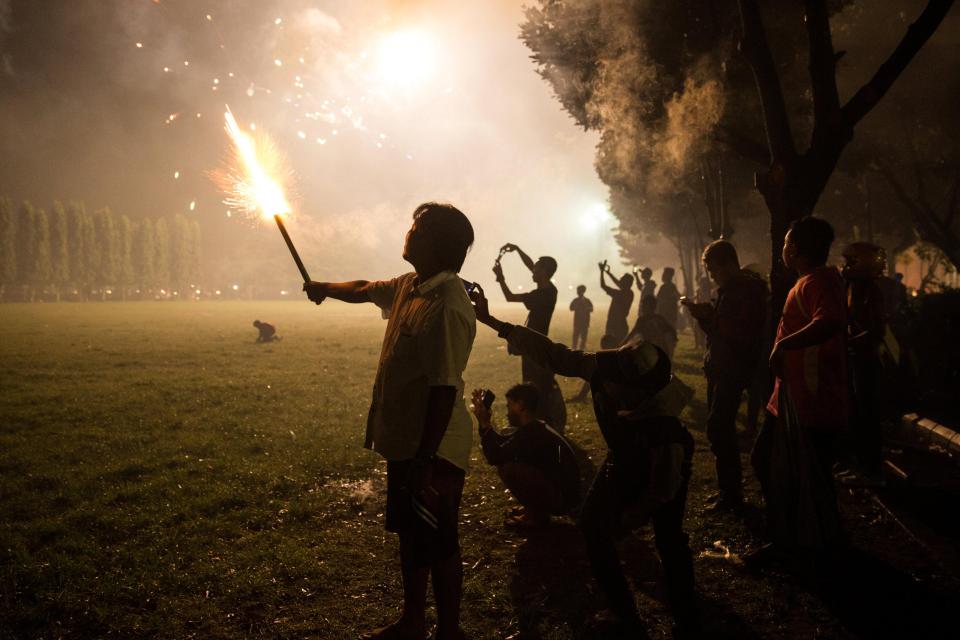  A man holds a spankler at the Bajra Sandhi Monument during New Year celebrations in Denpasar, Bali island, Indonesia