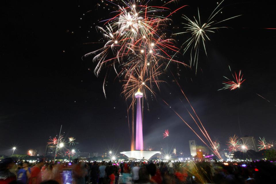  People watch fireworks explode around the National Monument during New Year's Eve celebrations in Jakarta, Indonesia