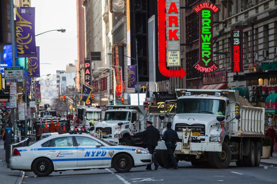  Police officers patrol Times Square as sand-filled sanitaion trucks are used as street barriers before New Year's eve celebrations