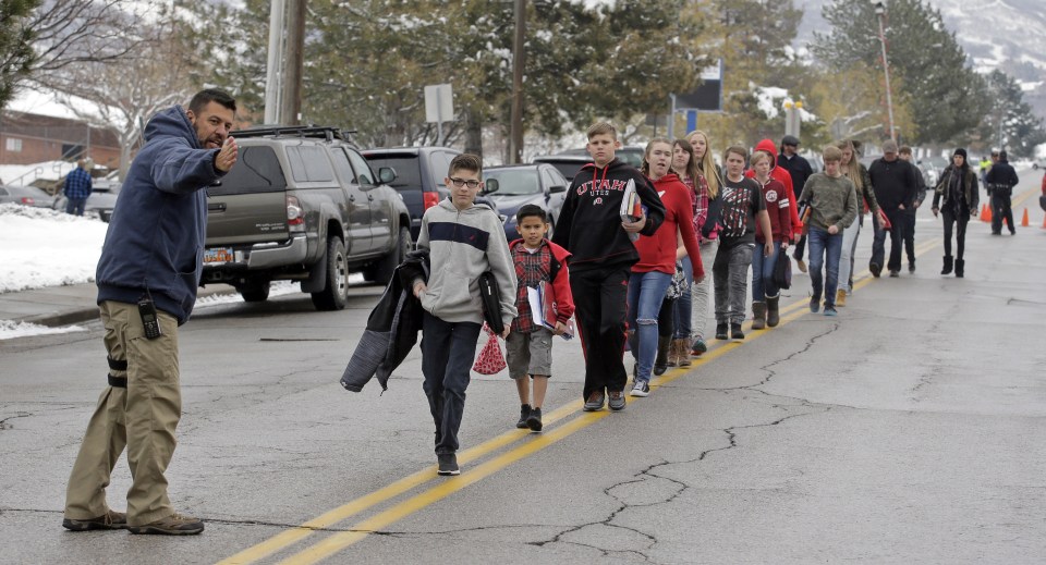  A police officer directs students down the street following the school lockdown