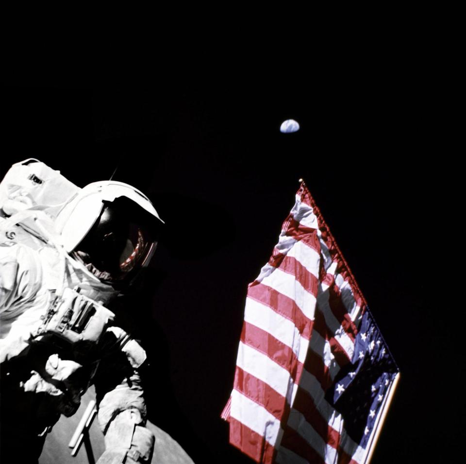  Eugene Cernan holds the lower corner of an American flag during the mission Apollo 17