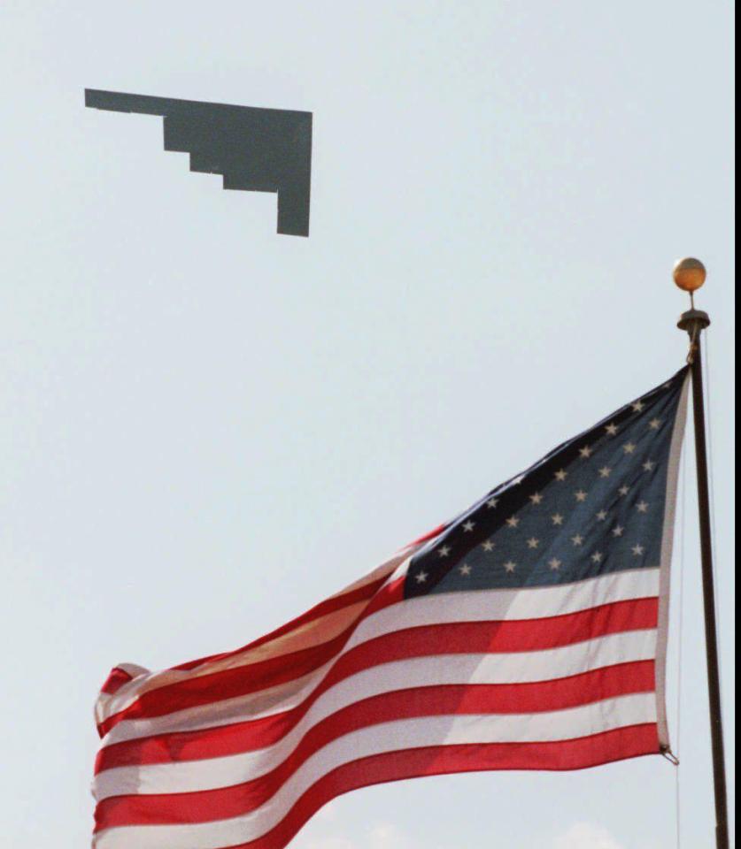  A B-2 stealth bomber takes off from Whiteman Air Force Base past an American flag