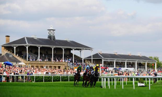 Runners in the DFS Doncaster Cup race past the grandstands at Doncaster Racecourse on September 11, 2009