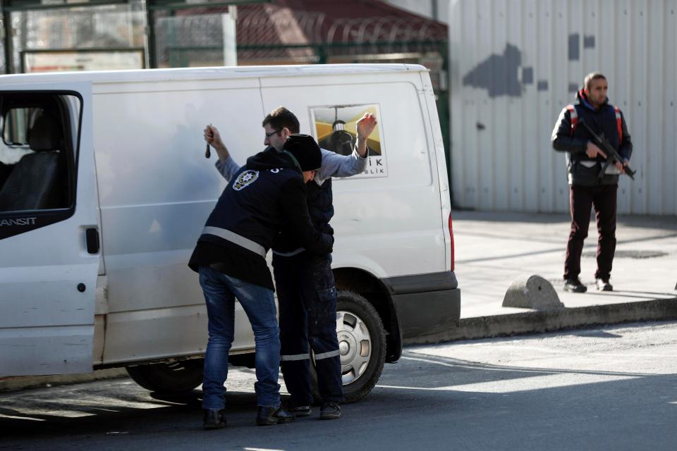  A Turkish police officer searches a person near the scene a day after the attack