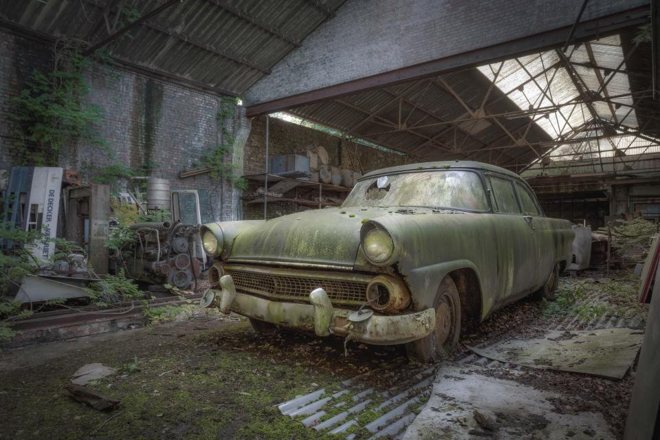  An abandoned car has a green hint to its bodywork after it was left in an old workshop