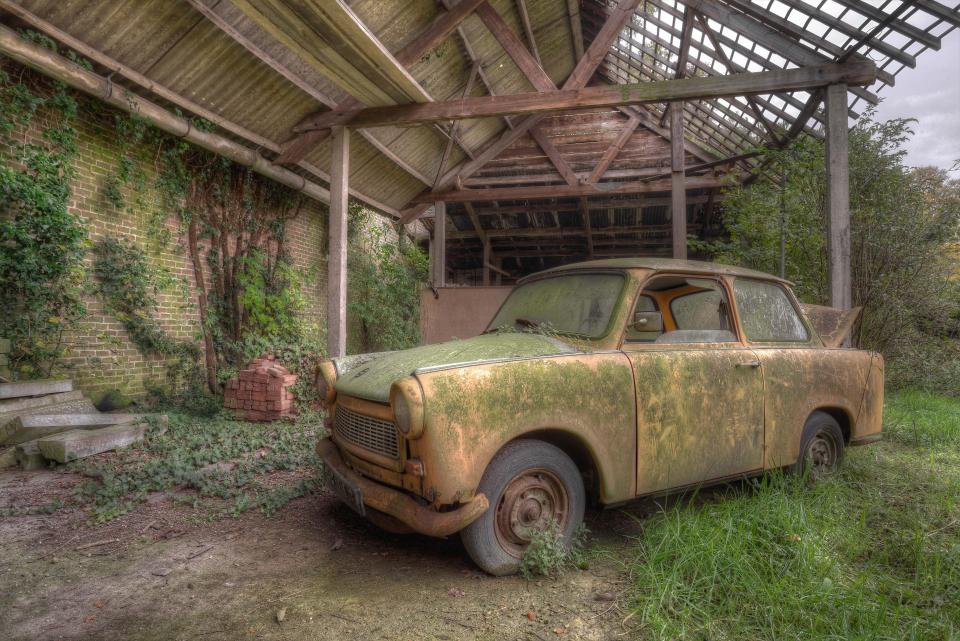  Green smudge covers the bodywork of this brick-coloured vintage car that was left outside a building