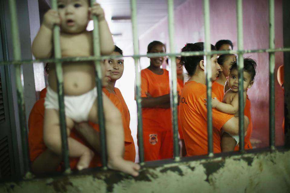  An inmate holds a baby while greeting visitors inside the prison, which was previously one of the country's most violent