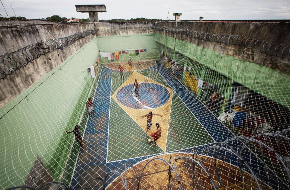  A football pitch emblazoned with the Brazilian flag surrounded by razor wire at a Manaus prison