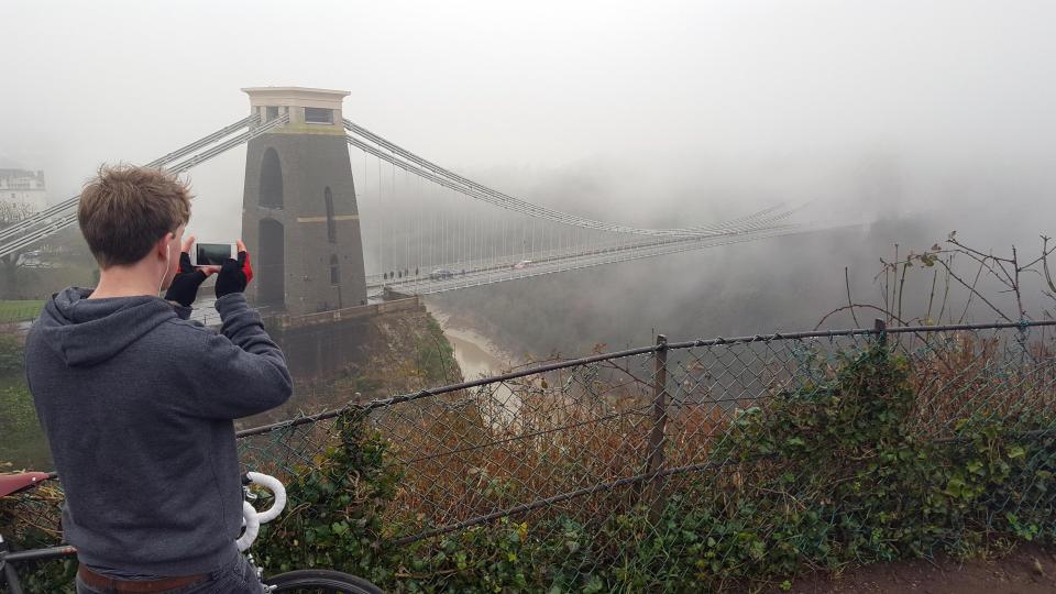  A cyclist takes a snap of the fog shrouding Clifton Suspension Bridge today