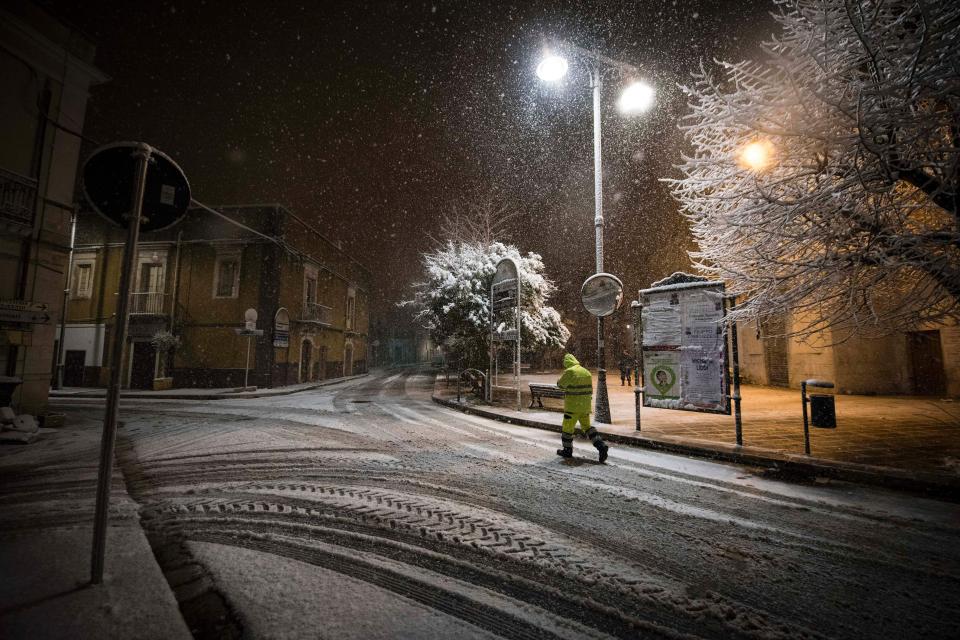  A lone emergency worker walks through the snow in the Italian town of Sammichele di Bari