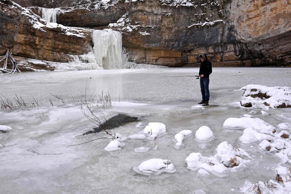  An ice fisher stands patiently beside a frozen waterfall near the Mirusha waterfalls, Kosovo