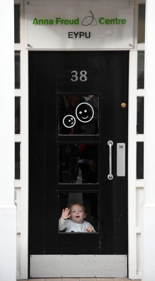  Riley, aged 15 months, presses her tiny hand against the glass pane of the door at the children's centre while waving goodbye to the Duchess