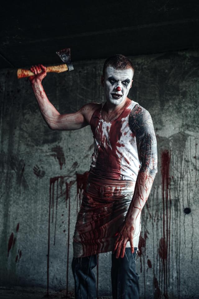  A stock photo of a "killer clown", not March in his costume, brandishing an axe while wearing bloody clothes and facepaint