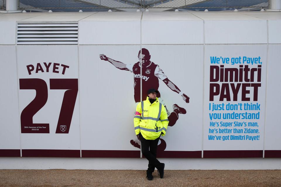  A West Ham security guard stands beside a club mural hailing their now-unsettled midfielder Dimitri Payet