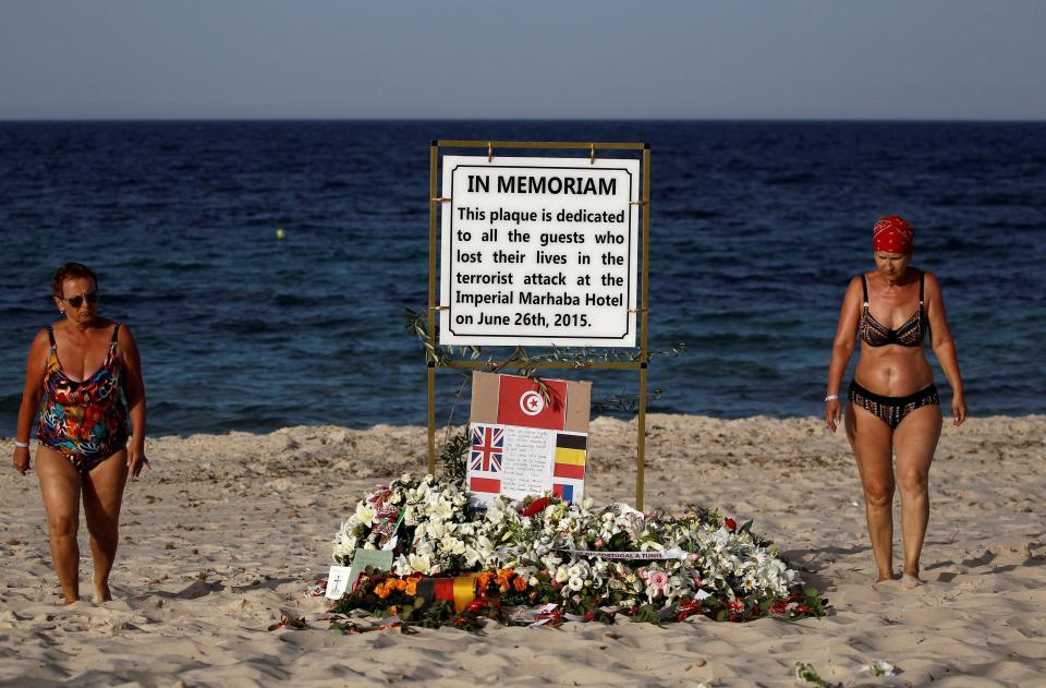  Tourists pass a plaque dedicated to victims on the beach of the Imperial Marhaba resort, on the first anniversary of an attack by a gunman at the hotel in Sousse, Tunisia