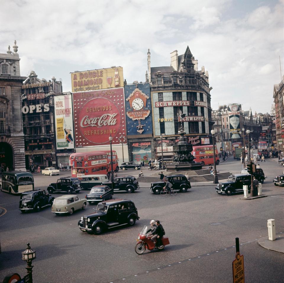  Cars and motorbikes drive past the billboards in the 1960s