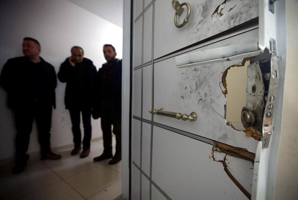  Reporters stand near the door to the flat which was blasted open by police on Monday night