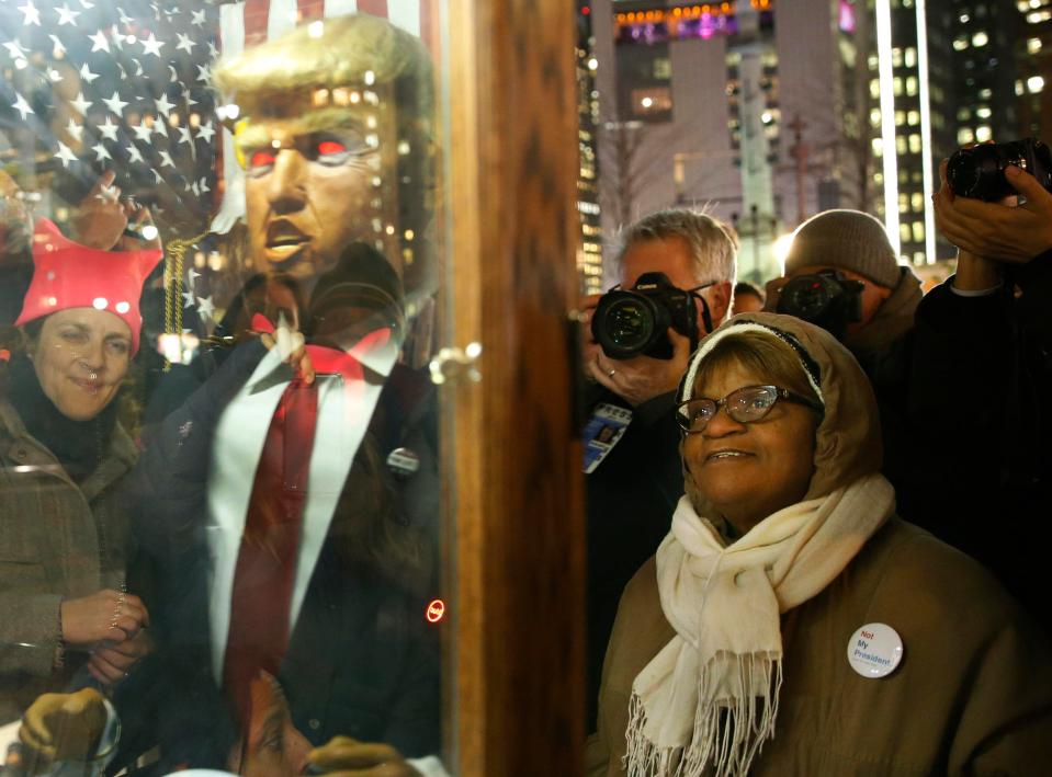  People gather around a talking Trump puppet