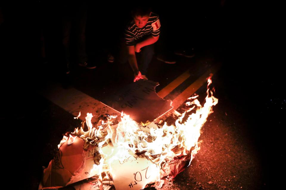  A youth adds to the burning pile of protest signs