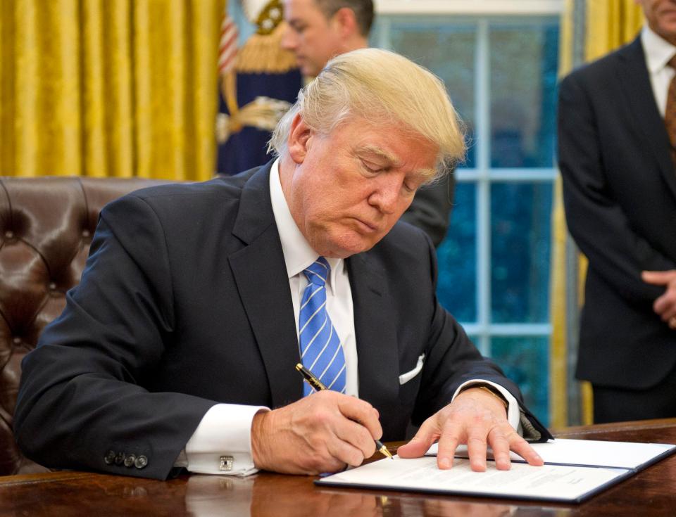  Donald Trump signs paperwork in the Oval Office