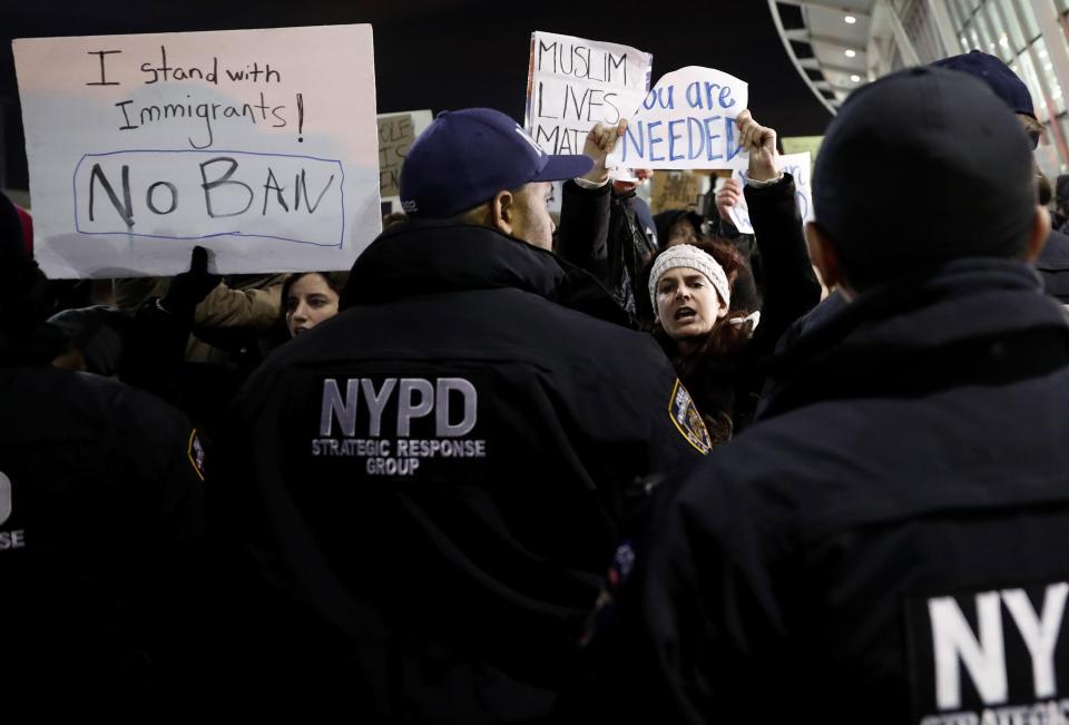  NYPD officers push protesters obstructing traffic away from the road while protesting President Donald Trump's immigration policies at JFK Airport