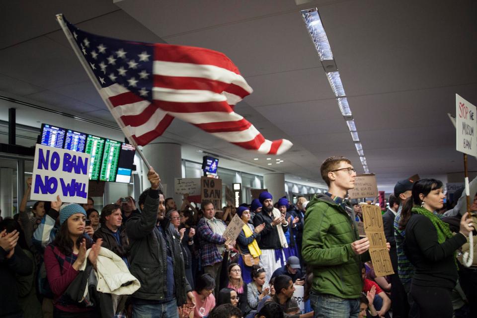  An American flag is waved at a protest in the arrivals terminal at San Francisco's SFO International Airport