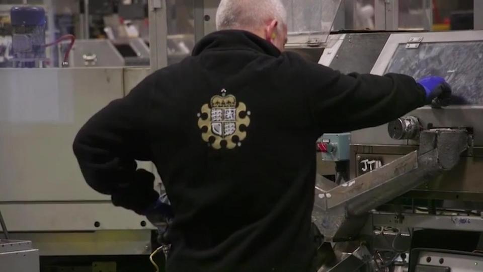  A worker inspects the coins as they are pressed out of the machines