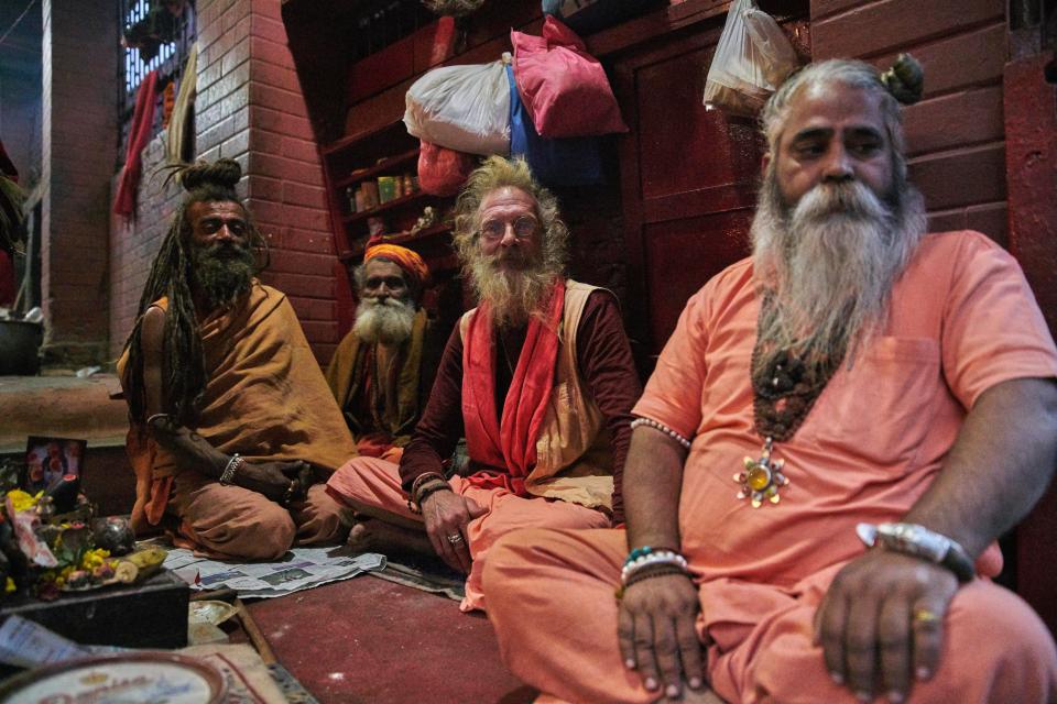  Four holymen - one European looking - sit in a buildingin Kathmandu