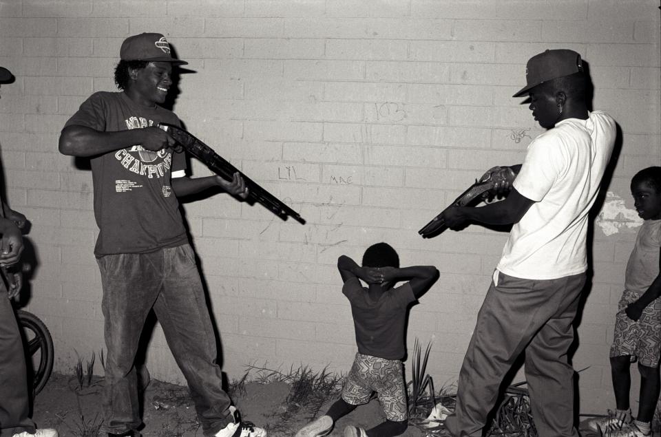  Members stage a mock execution of a young boy, pointing sawn-off shotguns at the child's head