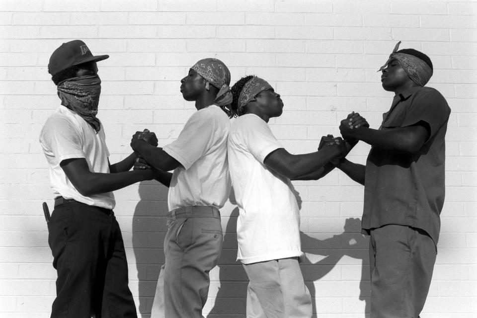  Wearing their trademark purple bandannas, members of the gang greet each other